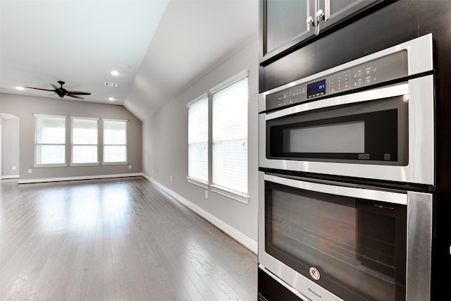 kitchen with hardwood / wood-style flooring, a healthy amount of sunlight, vaulted ceiling, and double oven