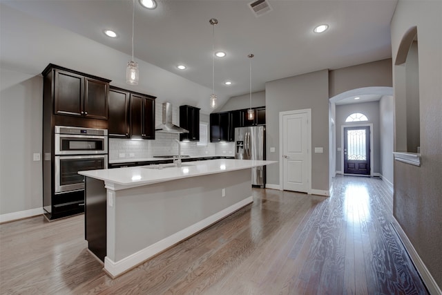 kitchen featuring backsplash, decorative light fixtures, wall chimney exhaust hood, and stainless steel appliances