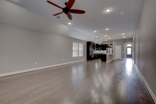 unfurnished living room with dark wood-type flooring, ceiling fan, and vaulted ceiling