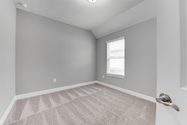 carpeted spare room with lofted ceiling