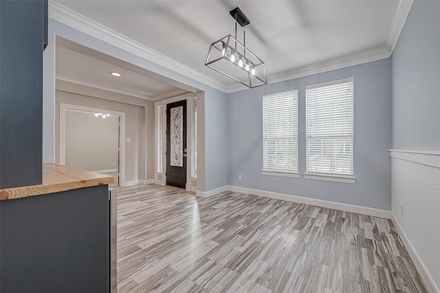 unfurnished dining area featuring light wood-type flooring and ornamental molding