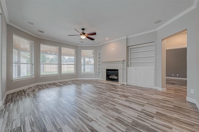 unfurnished living room featuring ceiling fan, built in features, light wood-type flooring, and ornamental molding