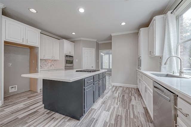 kitchen with sink, light hardwood / wood-style flooring, ornamental molding, appliances with stainless steel finishes, and white cabinetry