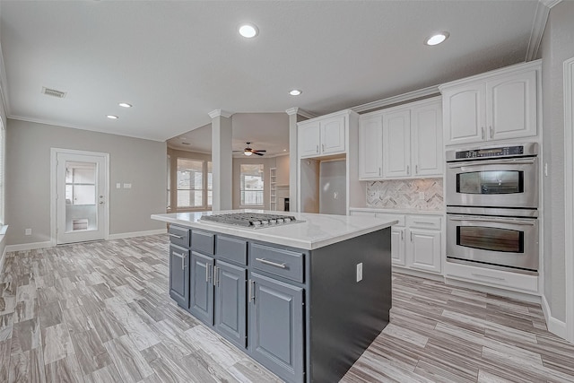 kitchen featuring appliances with stainless steel finishes, a center island, white cabinetry, and crown molding