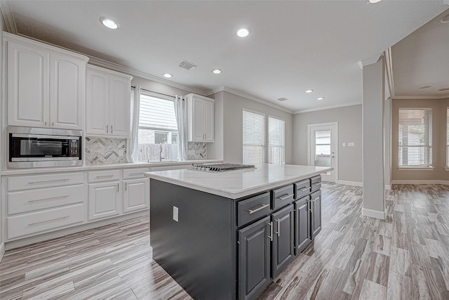 kitchen with stainless steel appliances, white cabinetry, and a healthy amount of sunlight