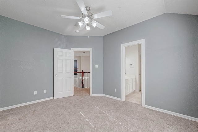 unfurnished bedroom featuring connected bathroom, ceiling fan, light carpet, and vaulted ceiling