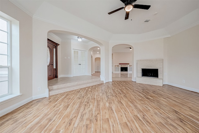 unfurnished living room featuring a fireplace, light hardwood / wood-style floors, ceiling fan, and ornamental molding