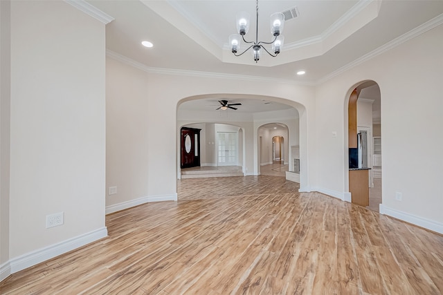 spare room with a tray ceiling, ornamental molding, and light wood-type flooring