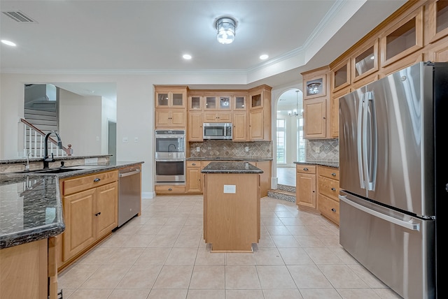 kitchen featuring a center island, dark stone counters, sink, ornamental molding, and stainless steel appliances