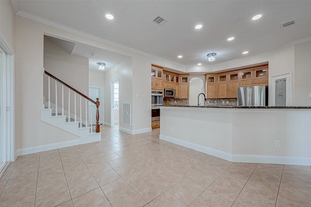 kitchen featuring tasteful backsplash, ornamental molding, dark stone counters, and appliances with stainless steel finishes