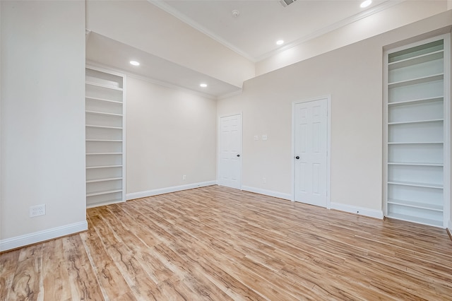 empty room featuring built in shelves, light hardwood / wood-style floors, and ornamental molding