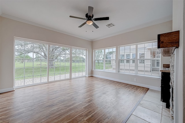 unfurnished sunroom featuring a fireplace, ceiling fan, and a healthy amount of sunlight