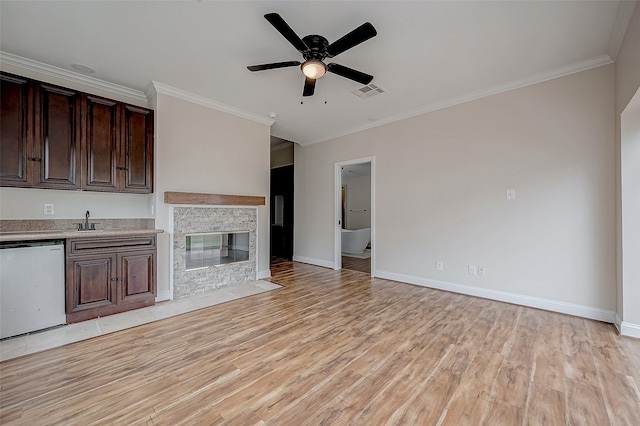 unfurnished living room with ceiling fan, sink, light wood-type flooring, a fireplace, and ornamental molding