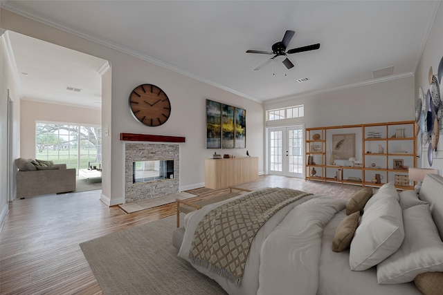 1810 Mccrary Rd, Richmond, TX 77406 - bedroom featuring multiple windows, ornamental molding, french doors, wood finished floors, and a stone fireplace