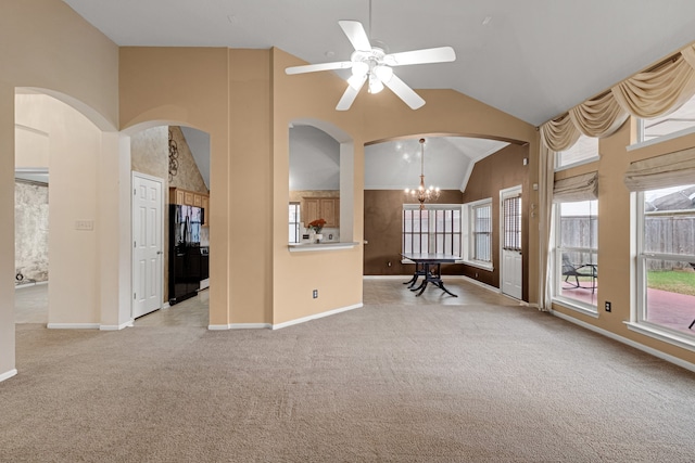 unfurnished living room with ceiling fan with notable chandelier, light colored carpet, and vaulted ceiling