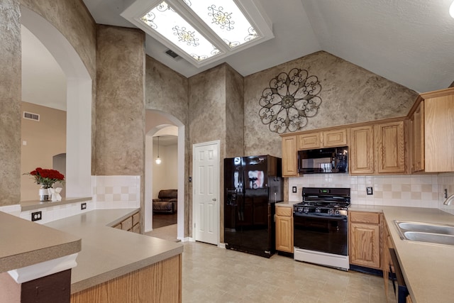 kitchen featuring kitchen peninsula, hanging light fixtures, black appliances, sink, and high vaulted ceiling