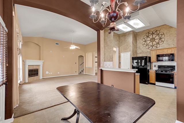 kitchen featuring black appliances, light brown cabinets, high vaulted ceiling, a high end fireplace, and light colored carpet