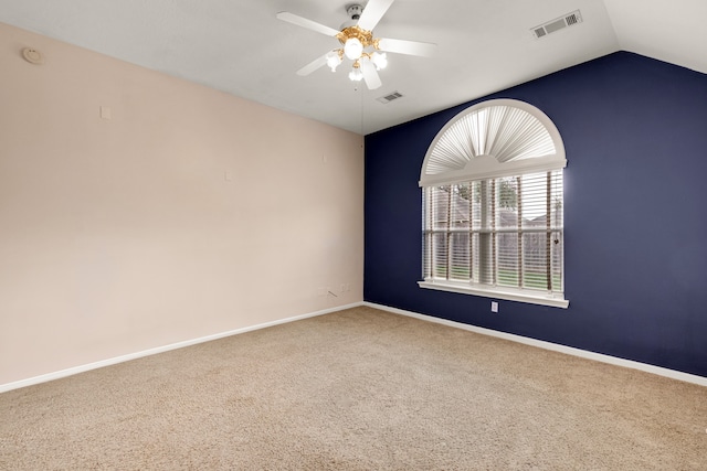 empty room featuring ceiling fan, vaulted ceiling, and carpet