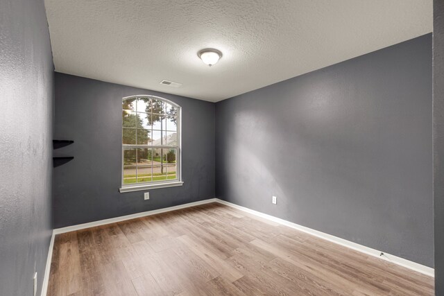 empty room with hardwood / wood-style floors and a textured ceiling