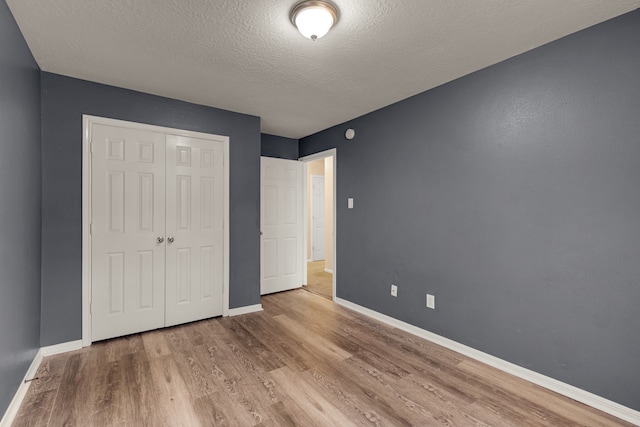 unfurnished bedroom with a closet, a textured ceiling, and light hardwood / wood-style flooring