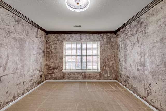 empty room with a textured ceiling, crown molding, and carpet floors