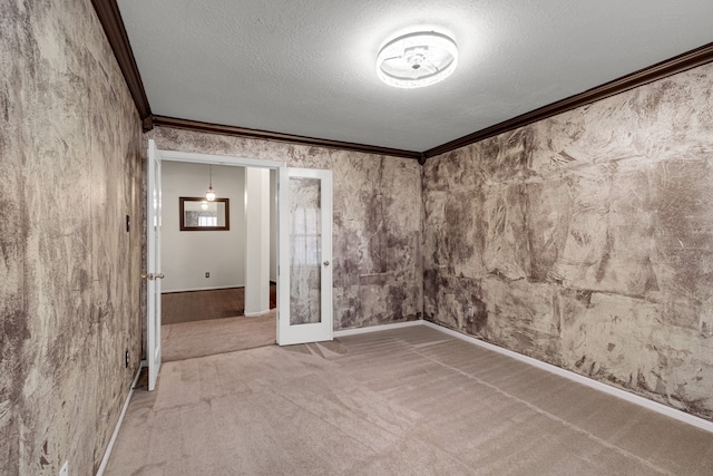 carpeted empty room featuring a textured ceiling, french doors, and ornamental molding