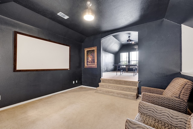 carpeted cinema with ceiling fan, a textured ceiling, and vaulted ceiling