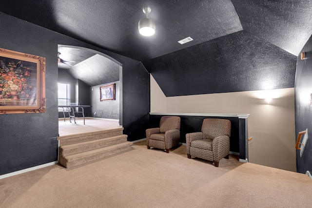 carpeted home theater featuring a textured ceiling and lofted ceiling