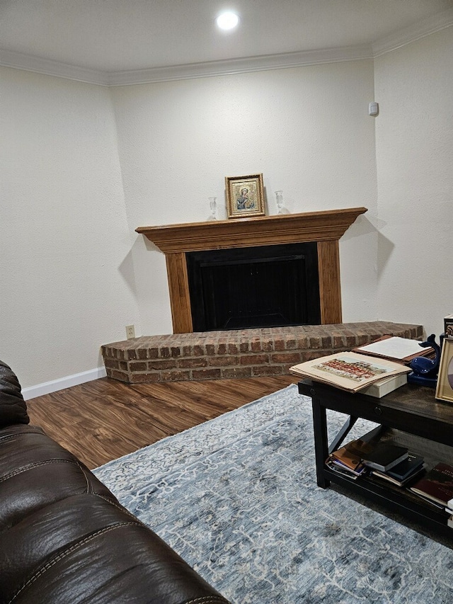 living room featuring hardwood / wood-style flooring, a brick fireplace, and crown molding