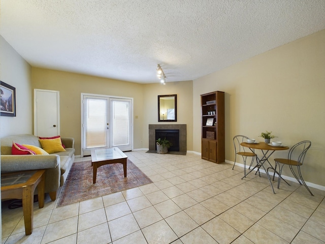 living room featuring a tiled fireplace, light tile patterned flooring, a textured ceiling, and french doors