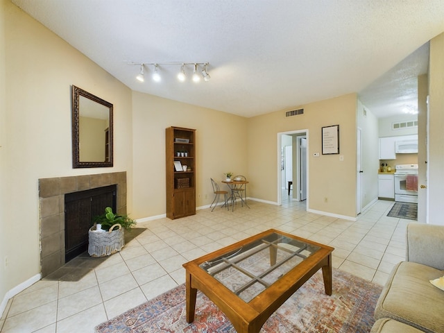 living room featuring a textured ceiling, a tile fireplace, and light tile patterned floors