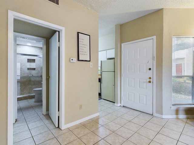 10855 Meadowglen Ln Unit 1112, Houston, TX 77042 - entryway featuring light tile patterned floors, a textured ceiling, and baseboards