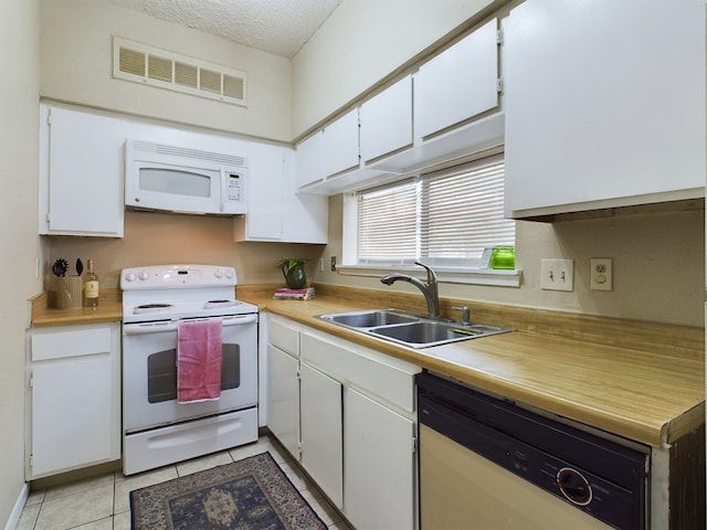kitchen featuring sink, light tile patterned floors, white cabinets, and white appliances