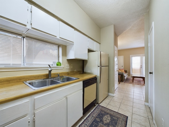 kitchen with sink, white appliances, a textured ceiling, white cabinets, and light tile patterned flooring
