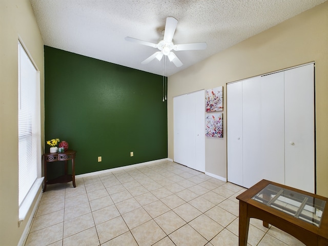 unfurnished bedroom featuring ceiling fan, light tile patterned floors, a textured ceiling, and a closet