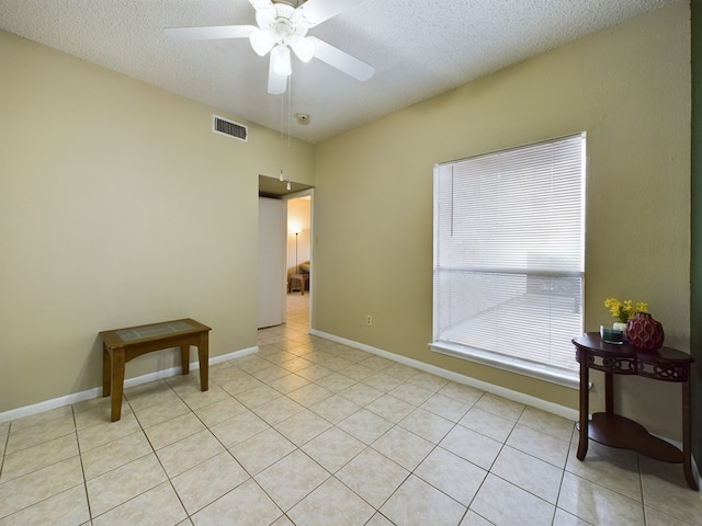 tiled empty room with a textured ceiling and ceiling fan
