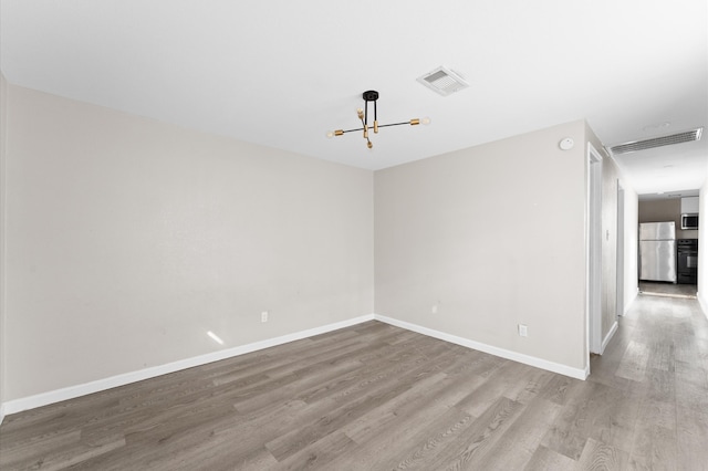 empty room featuring light hardwood / wood-style flooring and a notable chandelier