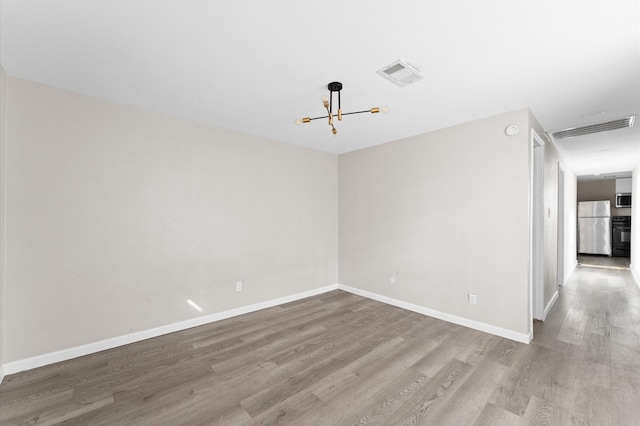 213 Super St, Houston, TX 77011 - spare room featuring wood finished floors, a chandelier, and baseboards