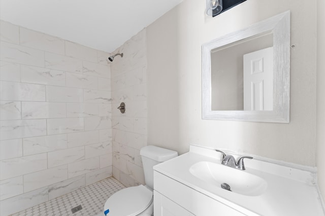 bathroom featuring vanity, toilet, and a tile shower