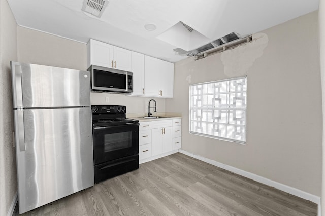 kitchen with stainless steel appliances, white cabinets, sink, and light wood-type flooring