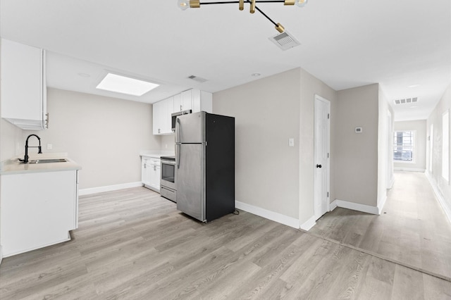 213 Super St, Houston, TX 77011 - kitchen featuring appliances with stainless steel finishes, a sink, light wood finished floors, and light countertops