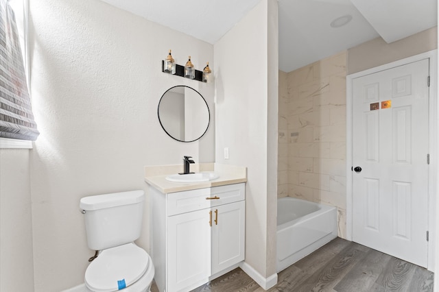 full bathroom featuring hardwood / wood-style floors, vanity, toilet, and tiled shower / bath