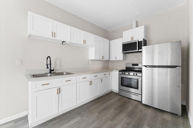 213 Super St, Houston, TX 77011 - kitchen with appliances with stainless steel finishes, a sink, dark wood-type flooring, white cabinetry, and light countertops