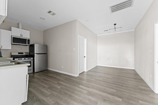 kitchen with white cabinetry, appliances with stainless steel finishes, light hardwood / wood-style floors, and crown molding