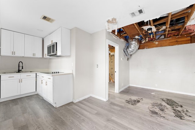 kitchen featuring black electric cooktop, white cabinetry, sink, and light wood-type flooring