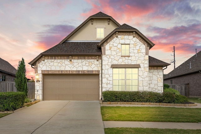 french country home with fence, stucco siding, a shingled roof, concrete driveway, and a garage