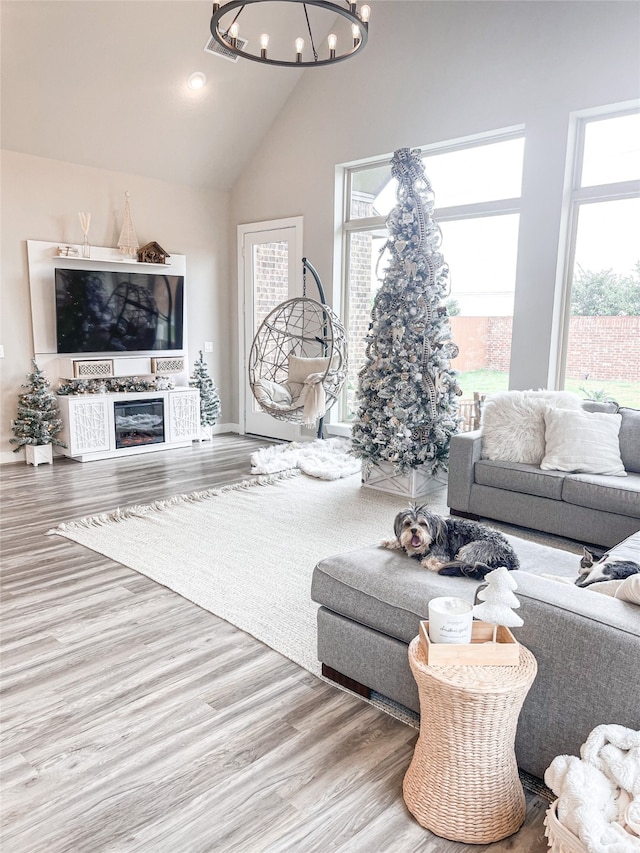 living room with lofted ceiling, wood-type flooring, a fireplace, and an inviting chandelier