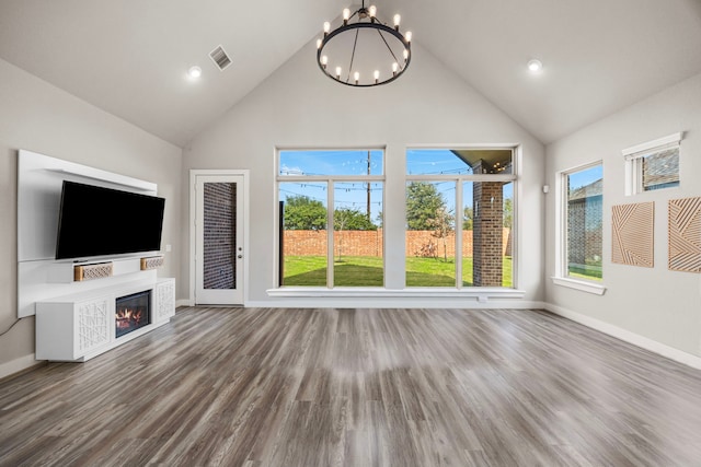 unfurnished living room with hardwood / wood-style flooring, a notable chandelier, and high vaulted ceiling