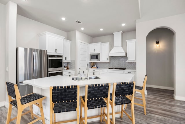 2215 Rose Manor Ct, Richmond, TX 77469 - kitchen with appliances with stainless steel finishes, custom range hood, a kitchen breakfast bar, baseboards, and light wood-style floors