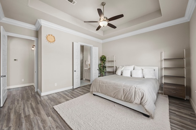 bedroom featuring ceiling fan, a raised ceiling, and ensuite bath